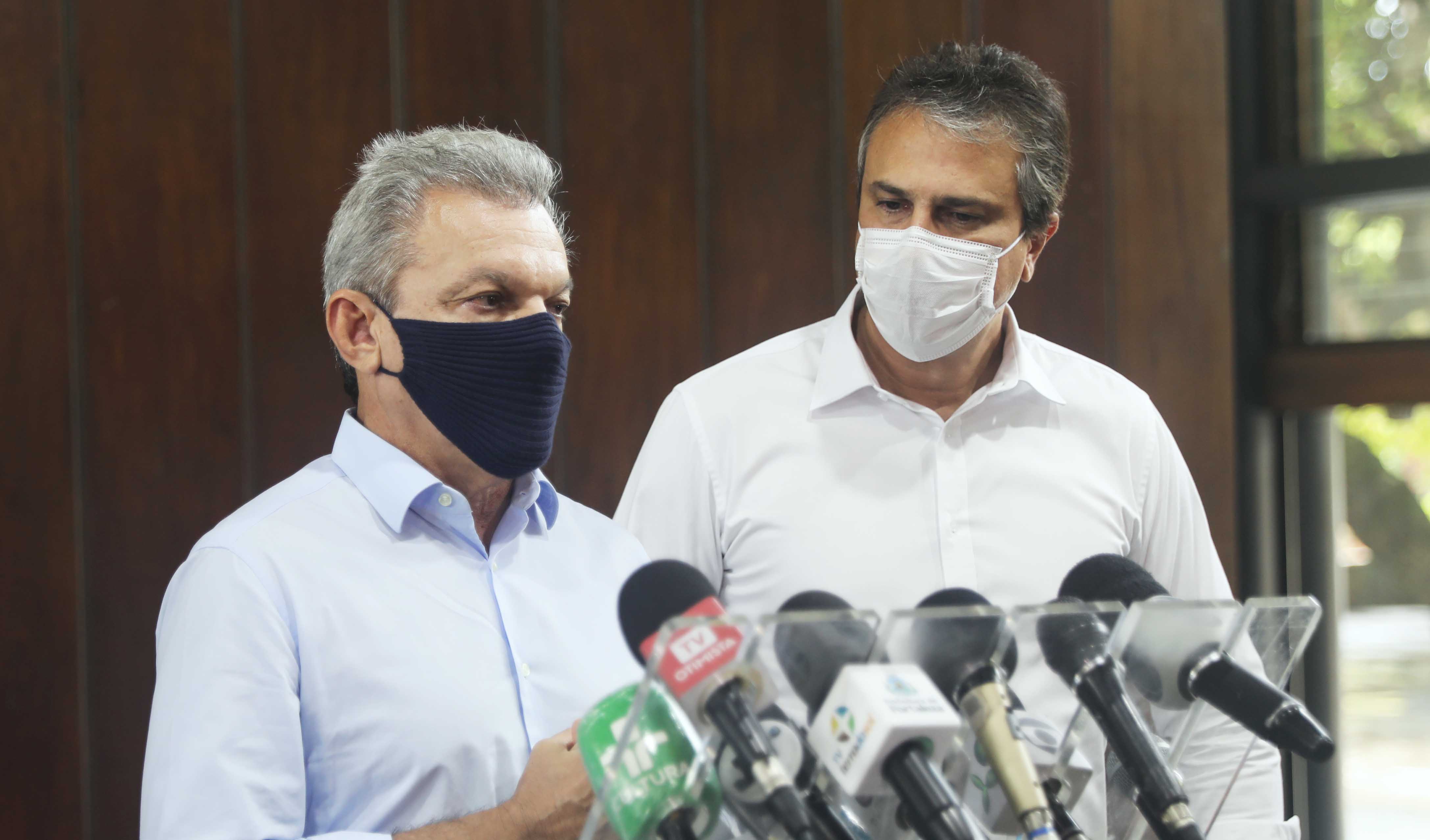 José Sarto falando em frente a microfones e Camilo ao lado direito olhando para ele